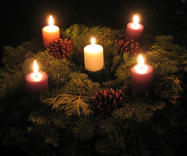 christmas wreath on table with acorns and 5 lit candles